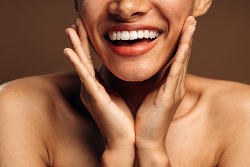 Cropped view of a girl smiling toothy while posing over brown studio background; How to Get White Teeth in One Day