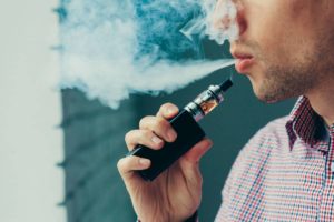 Mann benutzt einen Vape und raucht gerade aus