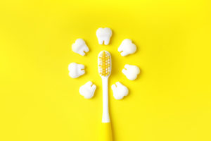 Zahnbürste mit Zähnen Modelle machen Sonne auf einem gelben Hintergrund. Zahnmedizinisches Konzept.