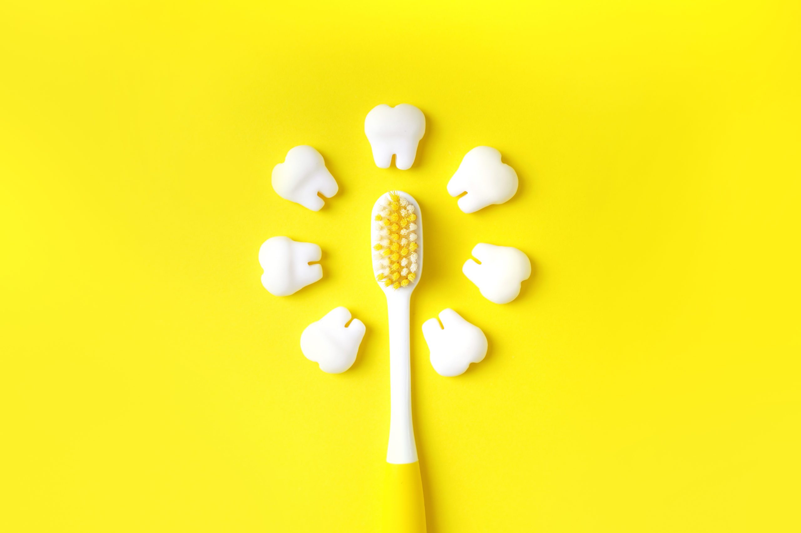 Zahnbürste mit Zähnen Modelle machen Sonne auf einem gelben Hintergrund. Zahnmedizinisches Konzept.