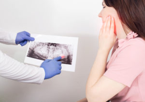 A dentist doctor is holding a panoramic X-ray picture of a female patient who has a dental abscess.