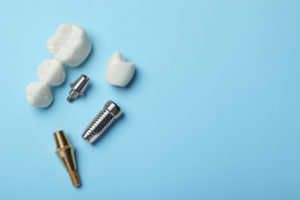Parts of dental implant and bridge on light blue background, flat lay