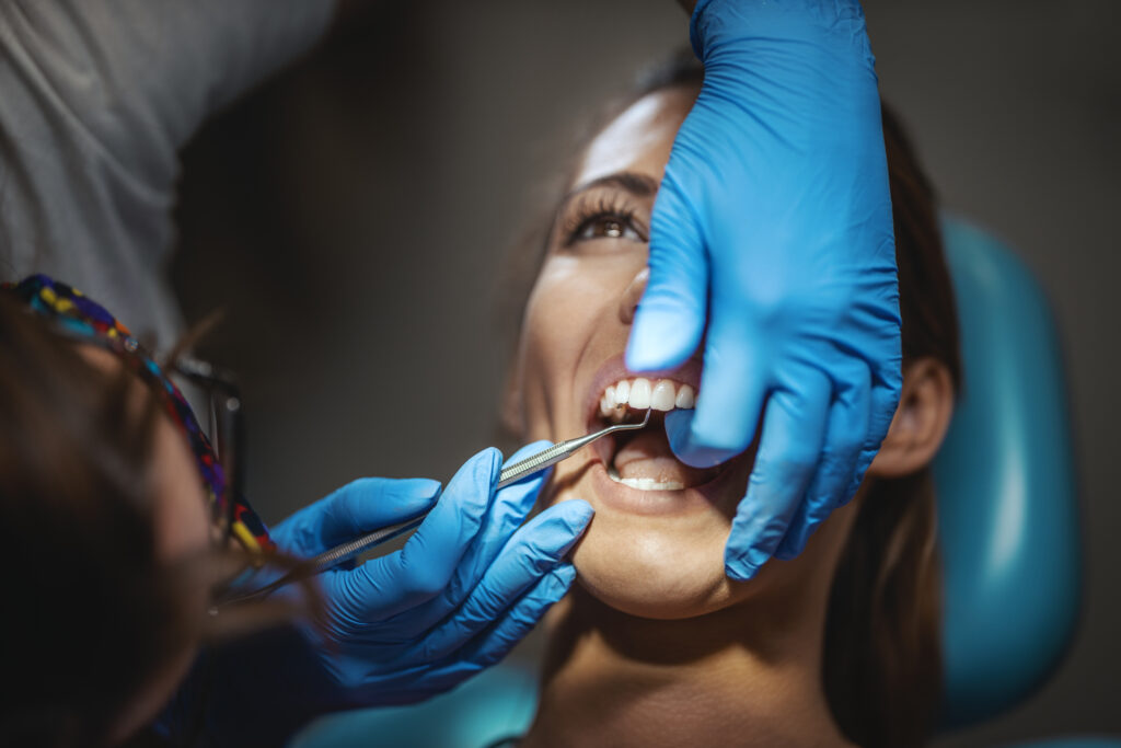 Young woman is at the dentist. She sits in the dentist's chair and gets a teeth bonding vs. veneers.