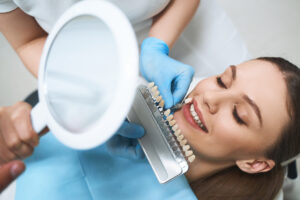 Happy woman taking care of teeth; dental veneers vs. lumineers