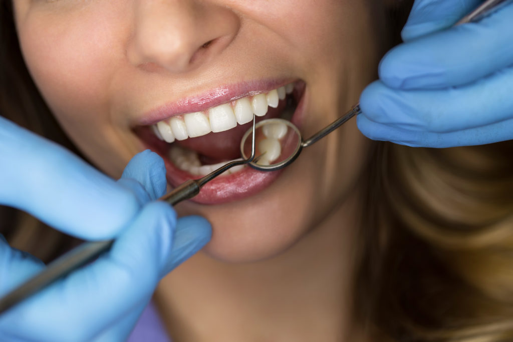 Zahnarzt untersucht die Zähne eines Patienten in der Zahnarztpraxis
