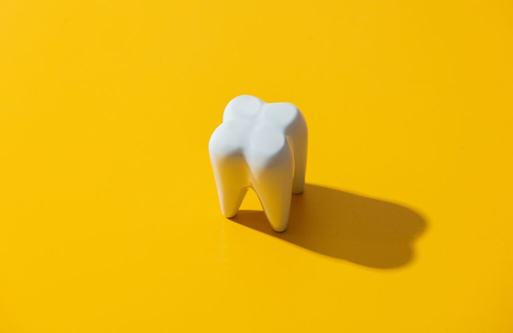 Yellow background with an artificial tooth; Tooth erosion