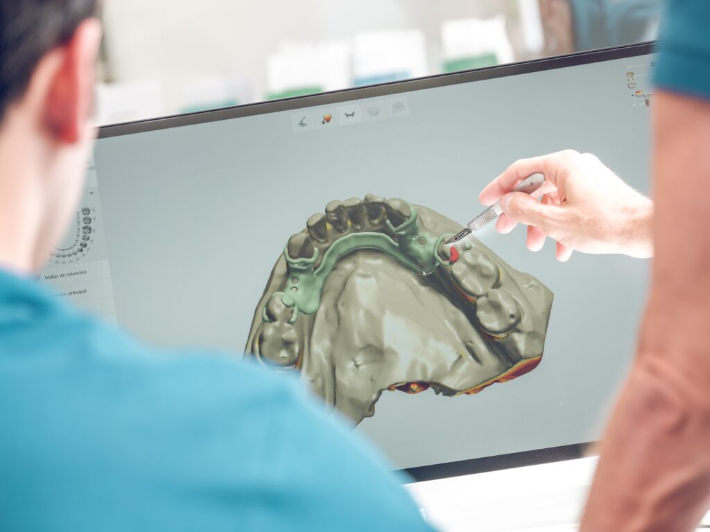 Zahnarzt zeigt auf den Bildschirm mit CAD CAM Technologie und Zahnmodell