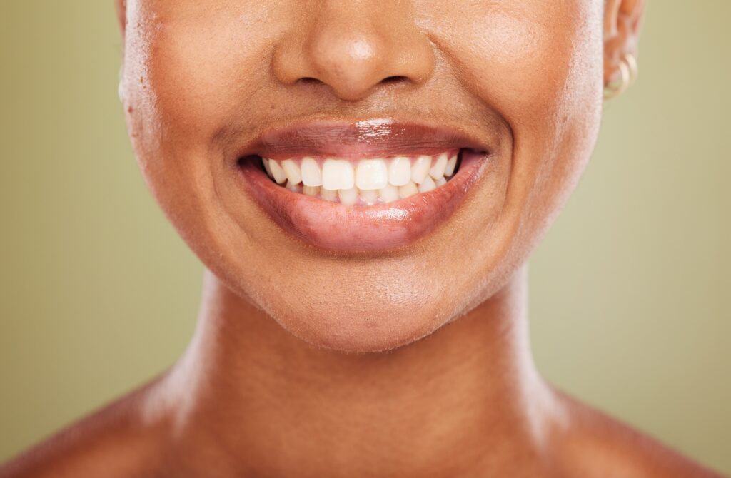 Smile, teeth and mouth of black woman closeup with front tooth crown